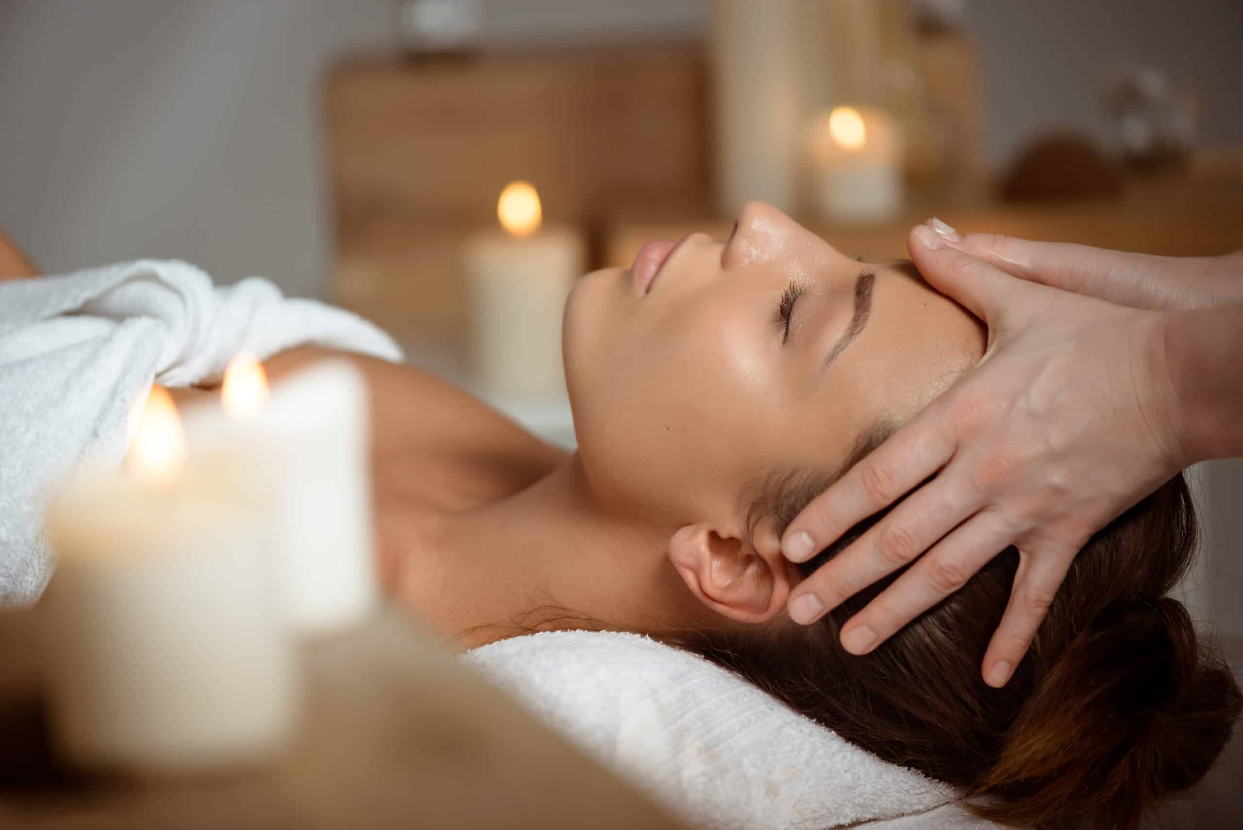 Young beautiful brunette girl having face massage relaxing in spa salon. Eyes closed. Copy space.